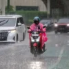 Foto Seorang pengendara kendaraan bermotor di Tengah Hujan deras.